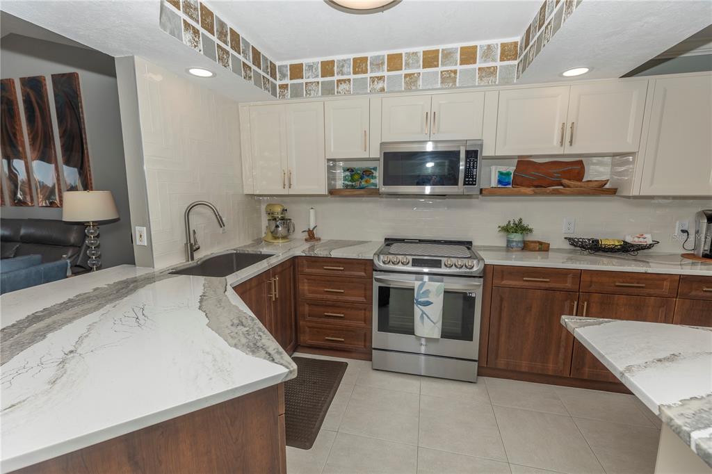 1401 South McCall Road, Unit B306 Englewood, FL 34223 - Photo 6 of 25 a kitchen with stainless steel appliances granite countertop a sink and a stove