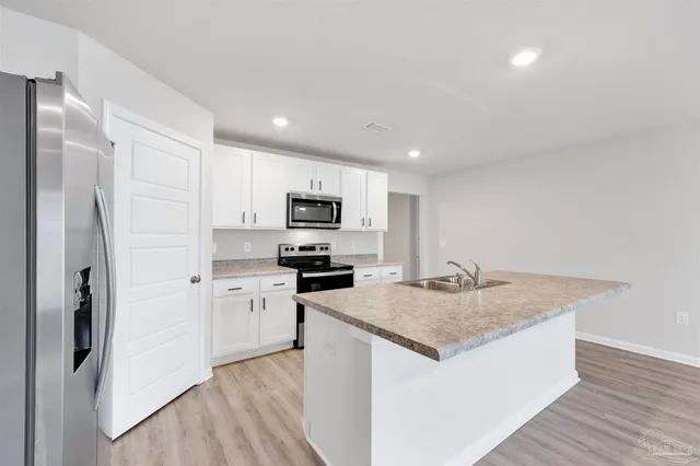 a kitchen with stainless steel appliances granite countertop a refrigerator a sink a stove a microwave and island