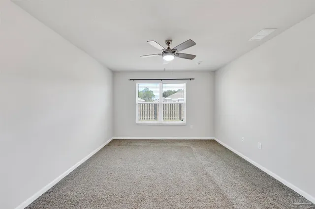 an empty room with a window and a ceiling fan