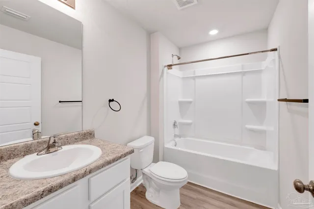 a bathroom with a granite countertop sink toilet mirror and shower