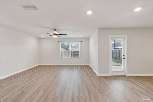 an empty room with wooden floor chandelier and windows