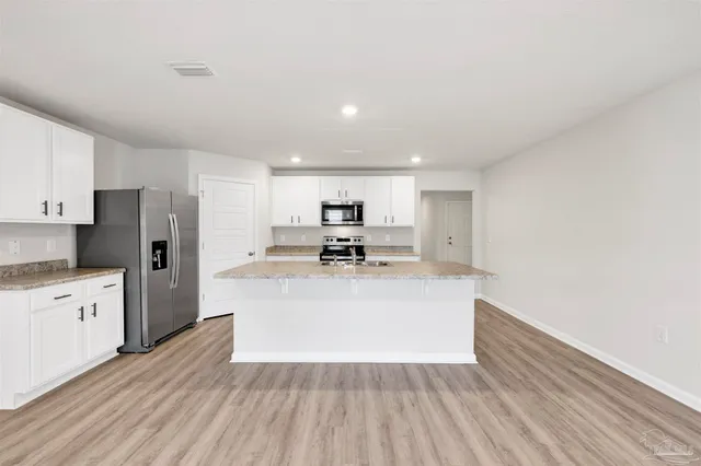 a view of kitchen with wooden floor stainless steel appliances and cabinets