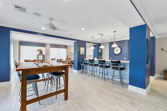 a dining hall with stainless steel appliances granite countertop a stove top oven a dining table and chairs with wooden floor