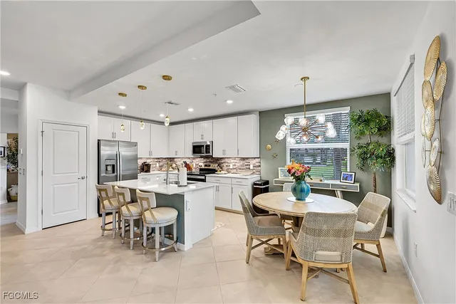 a view of a dining room and livingroom with furniture wooden floor a rug a flat screen tv a painting and a chandelier