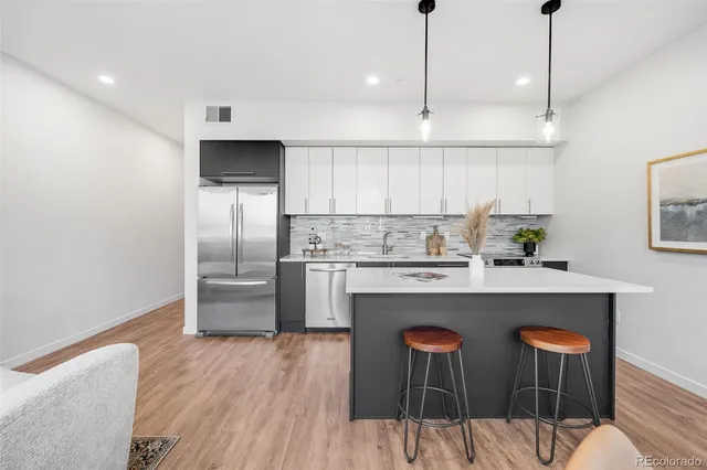 a kitchen with stainless steel appliances a dining table chairs sink and cabinets
