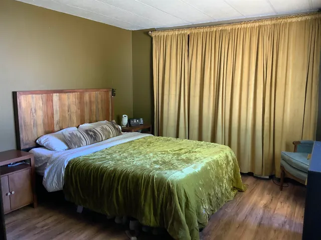 a bed sitting in a bedroom next to a window and a chair