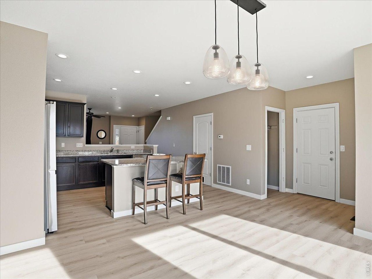 1565 Basildon Court Windsor, CO 80550 - Photo 14 of 36 a view of a kitchen with kitchen island stainless steel appliances wooden floor dining table and chairs