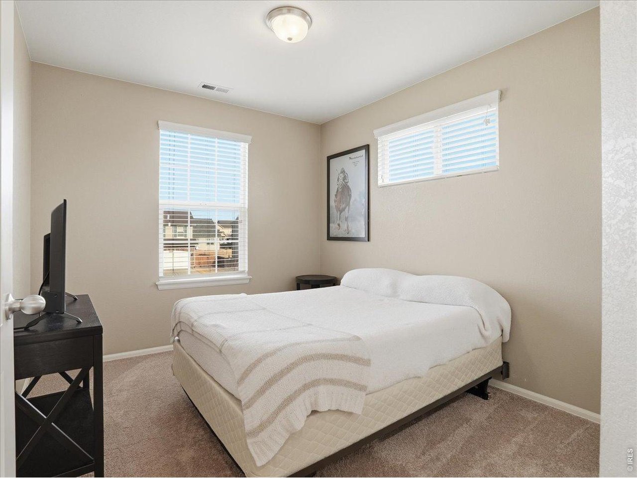 1565 Basildon Court Windsor, CO 80550 - Photo 18 of 36 a bedroom with a bed next to a window with a desk
