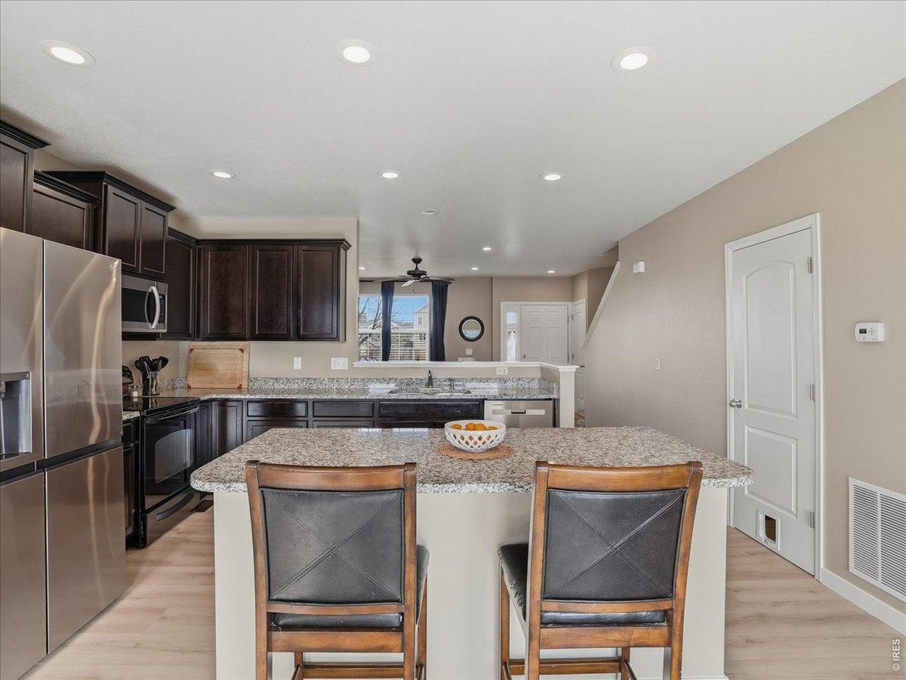 1565 Basildon Court Windsor, CO 80550 - Photo 9 of 36 a kitchen with a table chairs stove and refrigerator