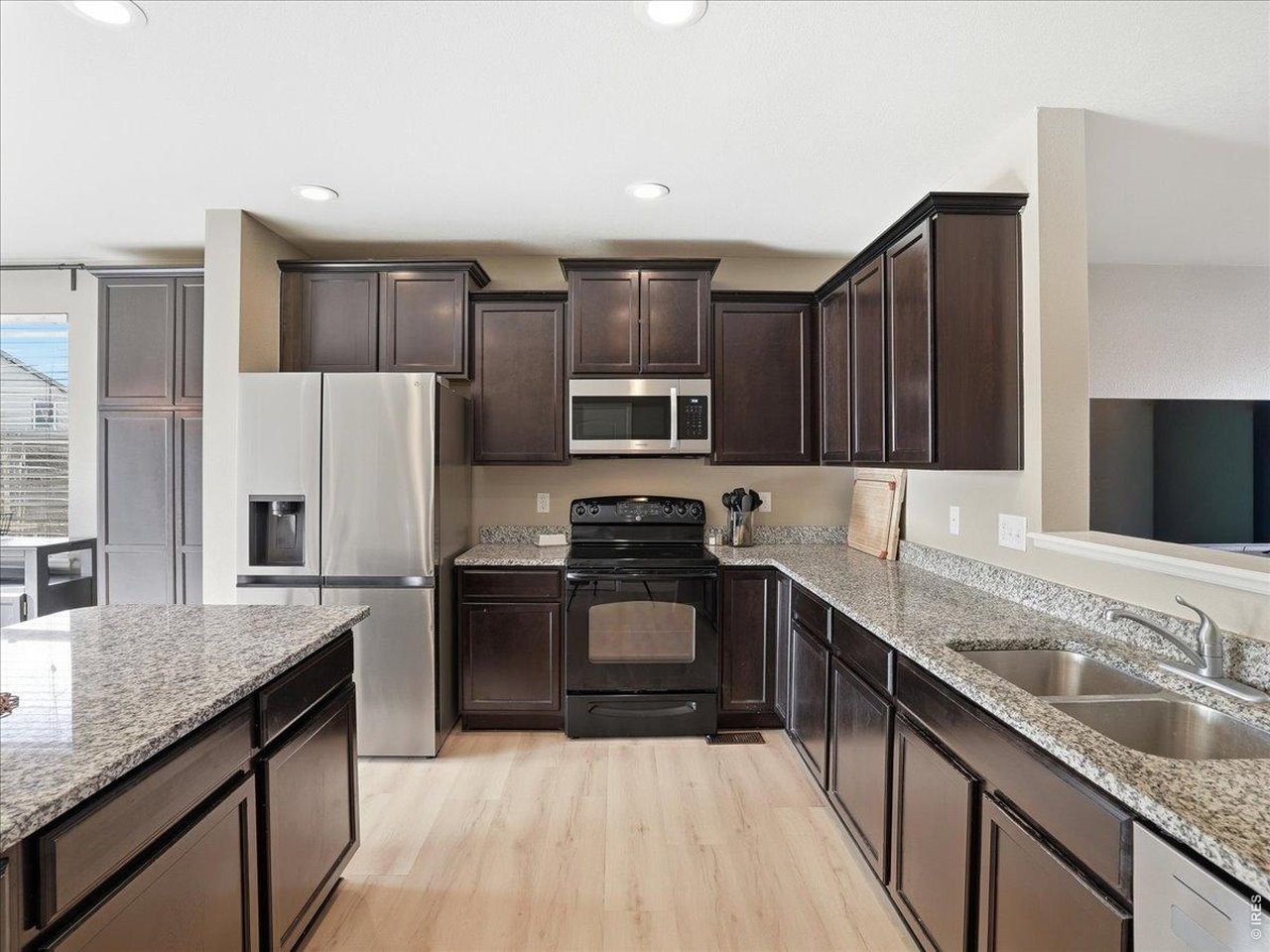 1565 Basildon Court Windsor, CO 80550 - Photo 10 of 36 a kitchen with stainless steel appliances granite countertop a sink stove microwave and refrigerator