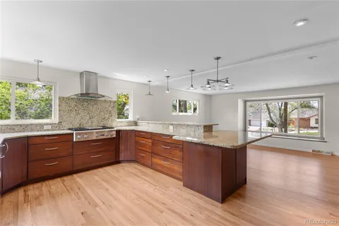 a kitchen with stainless steel appliances granite countertop a sink dishwasher stove and wooden cabinets with wooden floor