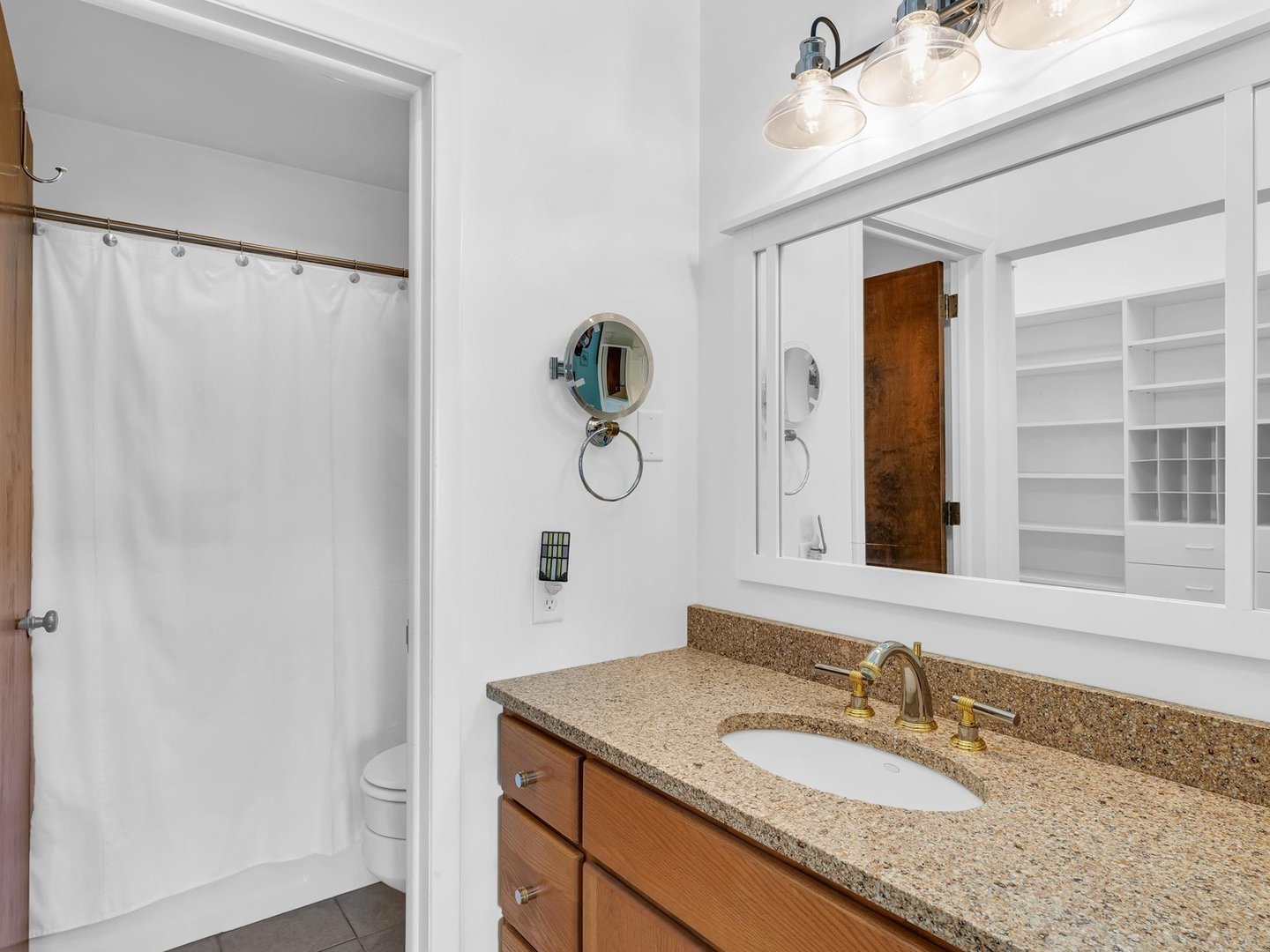 107 North Elm Street, Unit 310 Champaign, IL 61820 - Photo 22 of 34 a bathroom with a granite countertop sink a mirror and shower