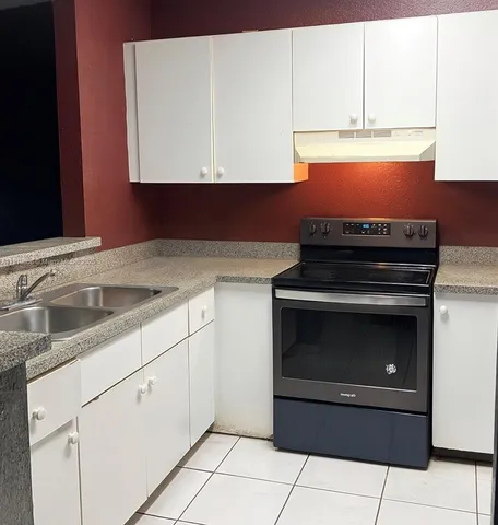 a kitchen with granite countertop white cabinets and appliances