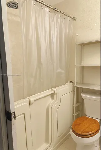a bathroom with a toilet and a shower curtain