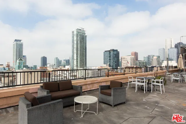 a view of a city from a roof deck with couches and potted plants