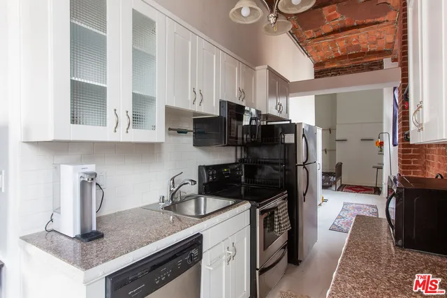 a kitchen with stainless steel appliances granite countertop a refrigerator a stove and a sink with wooden cabinets