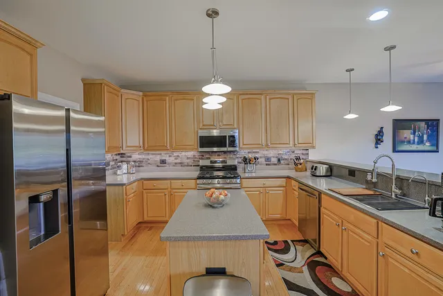a kitchen with stainless steel appliances granite countertop a sink a stove a refrigerator cabinets and chairs