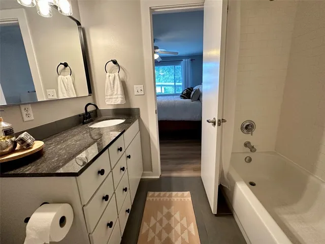 a bathroom with a granite countertop tub sink a mirror and a bathtub