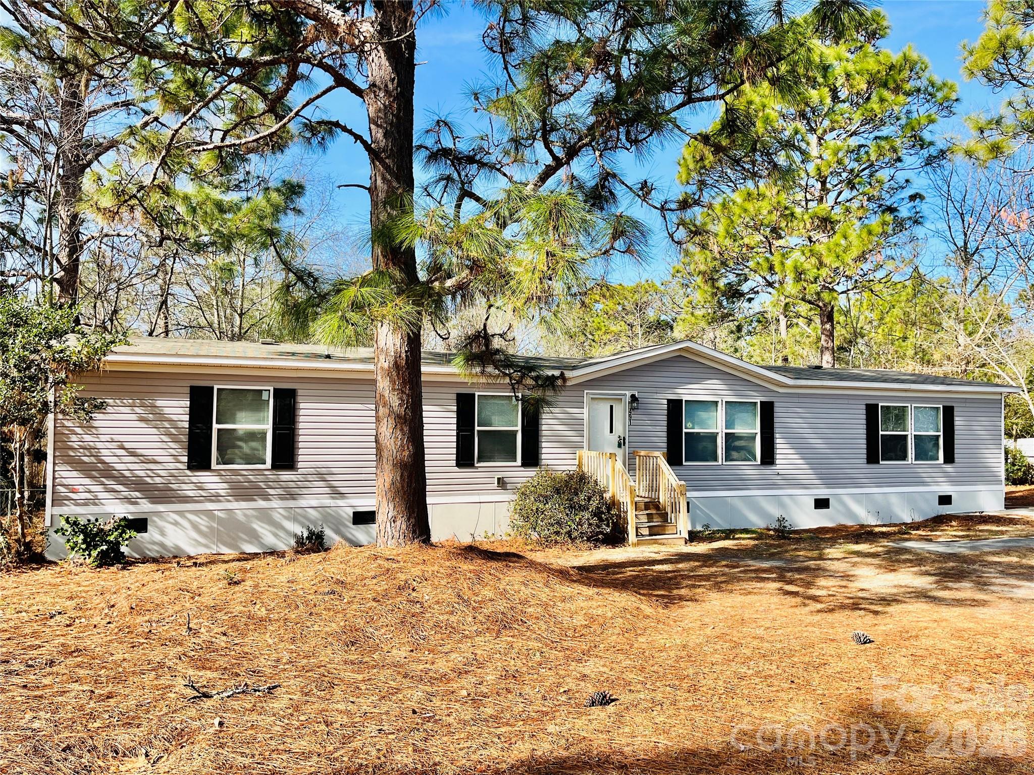 a front view of a house with a yard covered with snow and trees