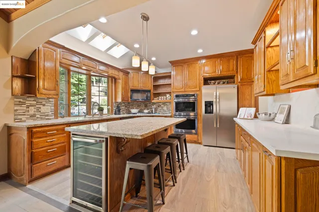 a kitchen with stainless steel appliances granite countertop wooden cabinets a dining table and chairs