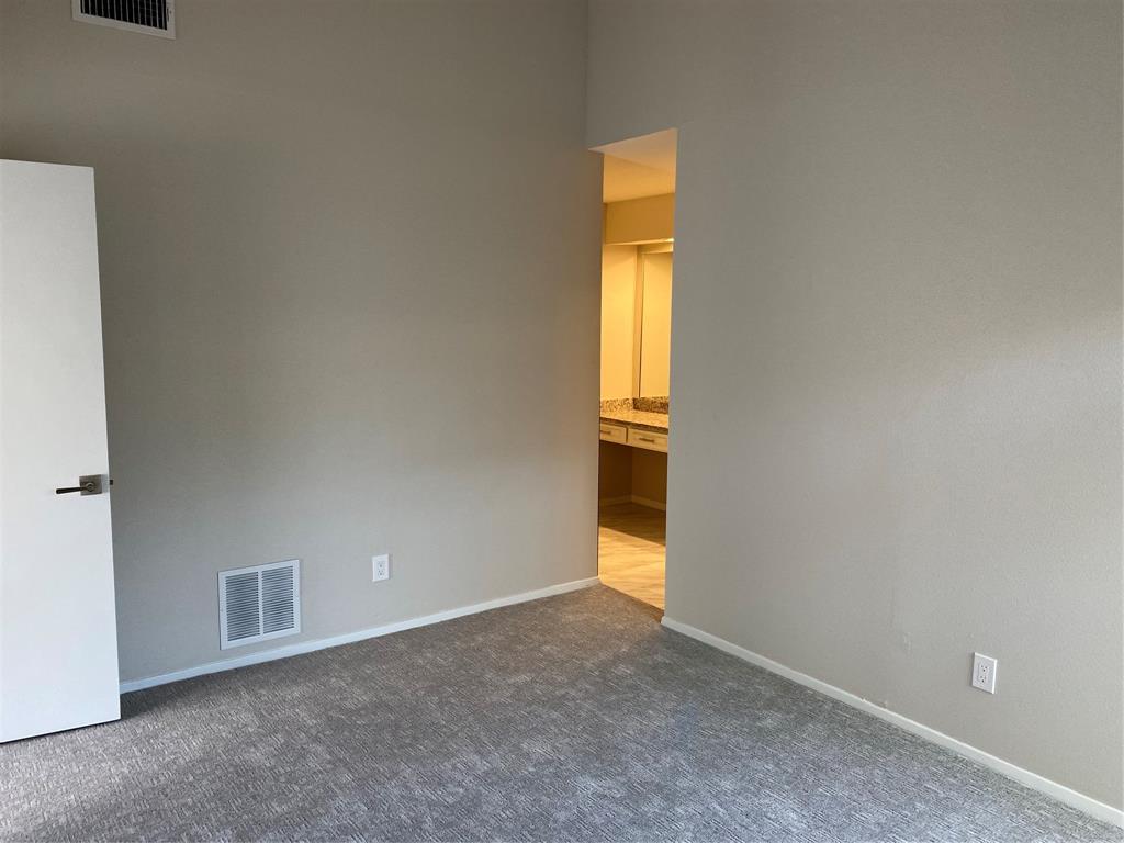 3936 Travis Street Dallas, TX 75204 - Photo 14 of 17 Carpeted room with neutral wall tones and a white interior door with contemporary hardware