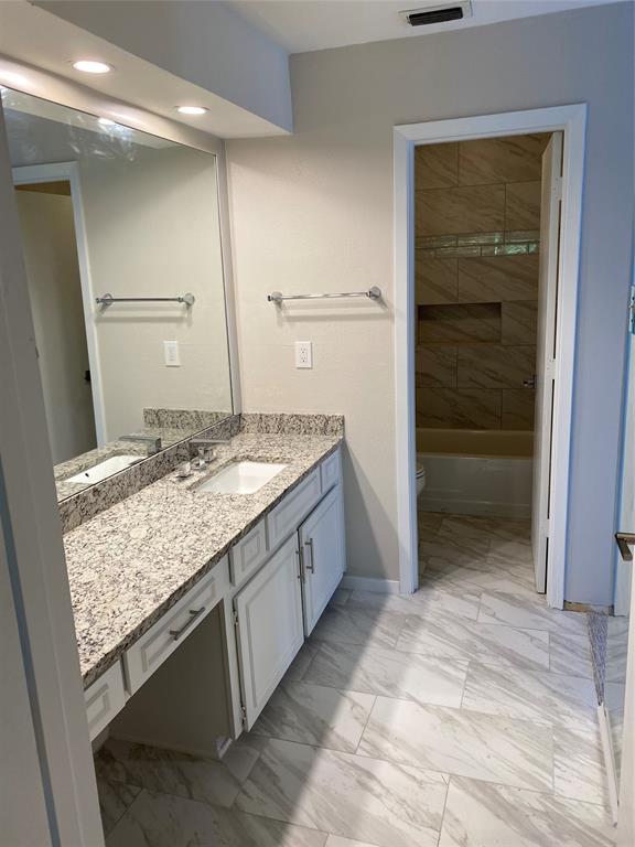 3936 Travis Street Dallas, TX 75204 - Photo 15 of 17 Bathroom featuring a vanity with a light granite-patterned countertop and an integrated sink