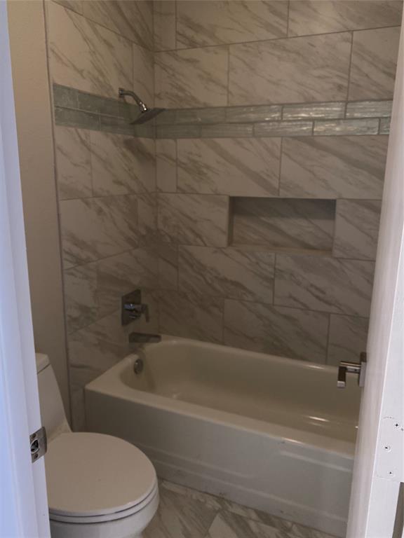 3936 Travis Street Dallas, TX 75204 - Photo 16 of 17 Shower-over-tub combination with large format marble-look tile, glass tile accent band, recessed shower niche, and a contemporary rainfall showerhead