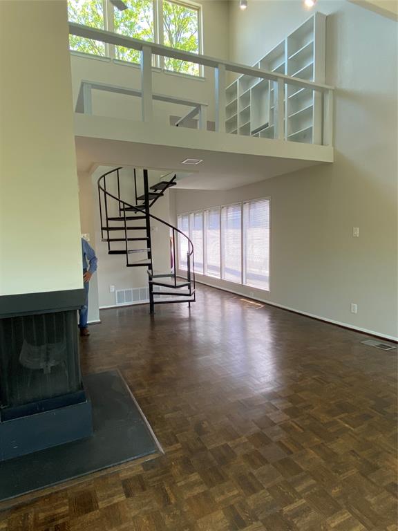 3936 Travis Street Dallas, TX 75204 - Photo 5 of 17 Living area featuring a black spiral staircase, wood-finish parquet flooring, and a floor-to-ceiling fireplace with a black hearth