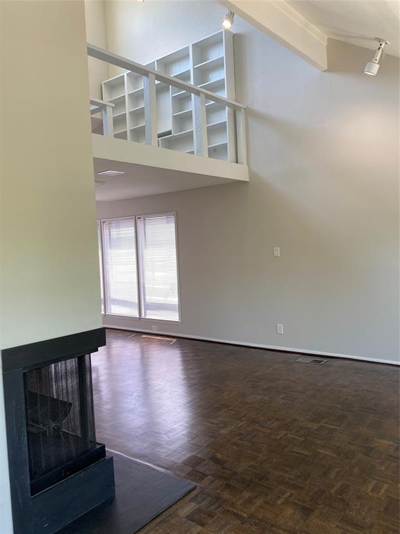 3936 Travis Street Dallas, TX 75204 - Photo 6 of 17 Spacious living area featuring a prominent fireplace with a dark hearth, parquet wood-finish flooring, and expansive windows