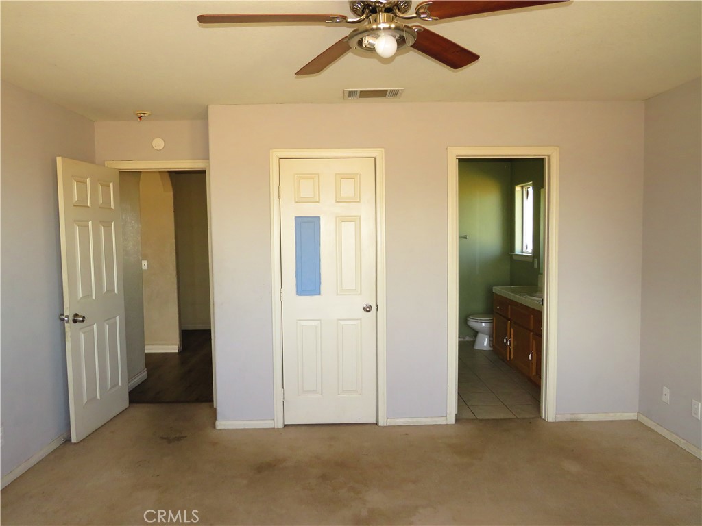 9951 Arrowhead Road Phelan, CA 92371 - Photo 17 of 21 an empty room that has a mirror and a chandelier fan