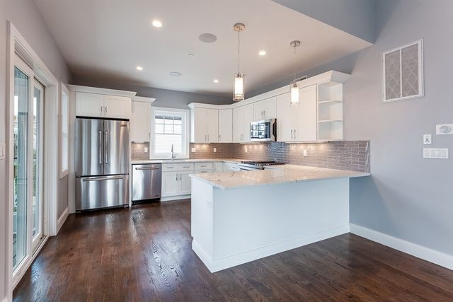 a kitchen with stainless steel appliances granite countertop a refrigerator a sink dishwasher a stove and white countertops with wooden floor