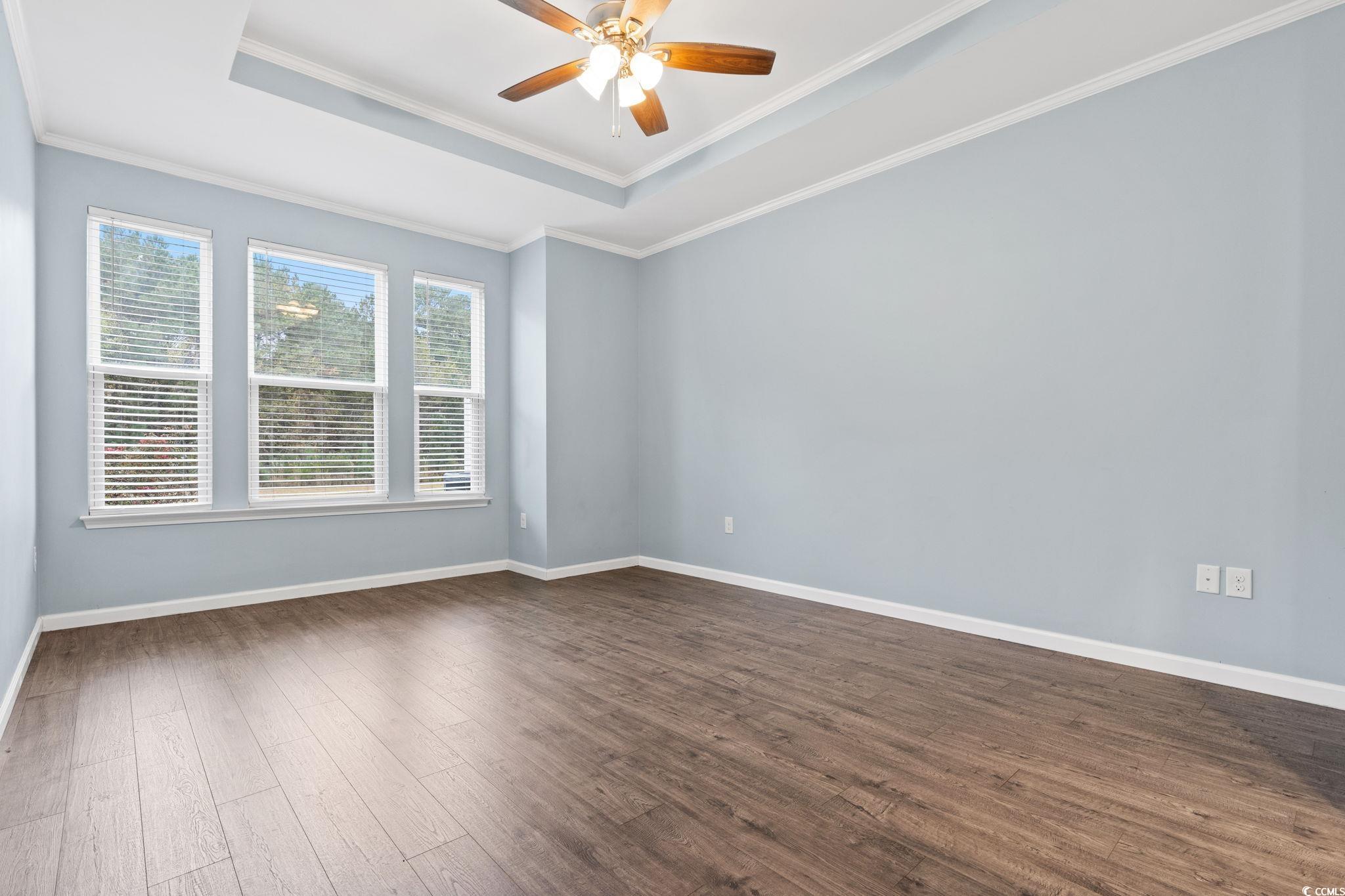 797 Salerno Circle, Unit C Myrtle Beach, SC 29579 - Photo 12 of 40 Empty room with a raised ceiling, dark wood-style floors, crown molding, and ceiling fan
