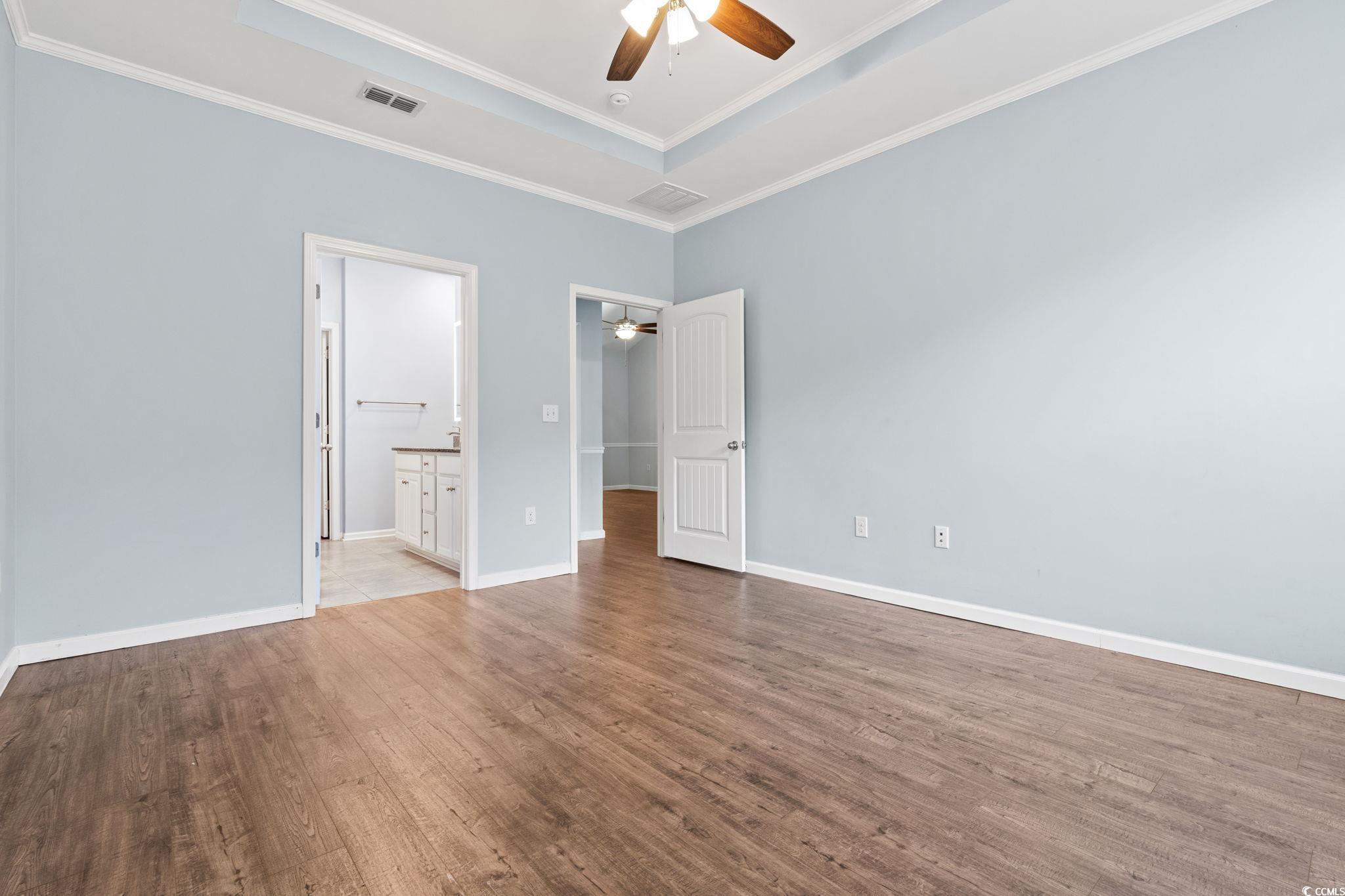 797 Salerno Circle, Unit C Myrtle Beach, SC 29579 - Photo 14 of 40 Unfurnished bedroom with a raised ceiling, wood finished floors, a ceiling fan, connected bathroom, and ornamental molding