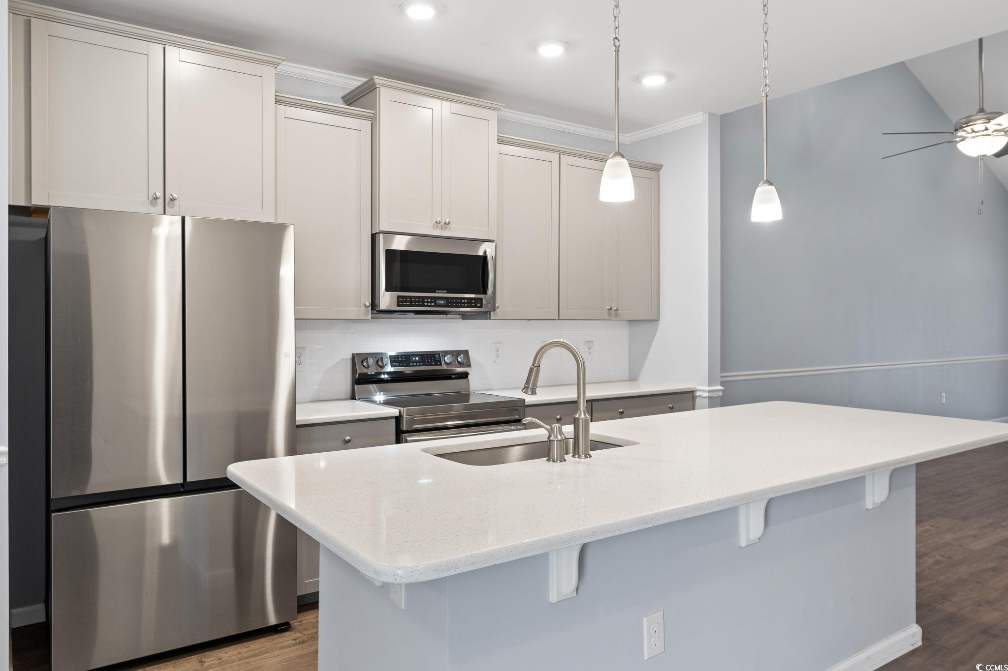 797 Salerno Circle, Unit C Myrtle Beach, SC 29579 - Photo 4 of 40 Kitchen featuring appliances with stainless steel finishes, dark wood-type flooring, light stone counters, ornamental molding, and hanging light fixtures