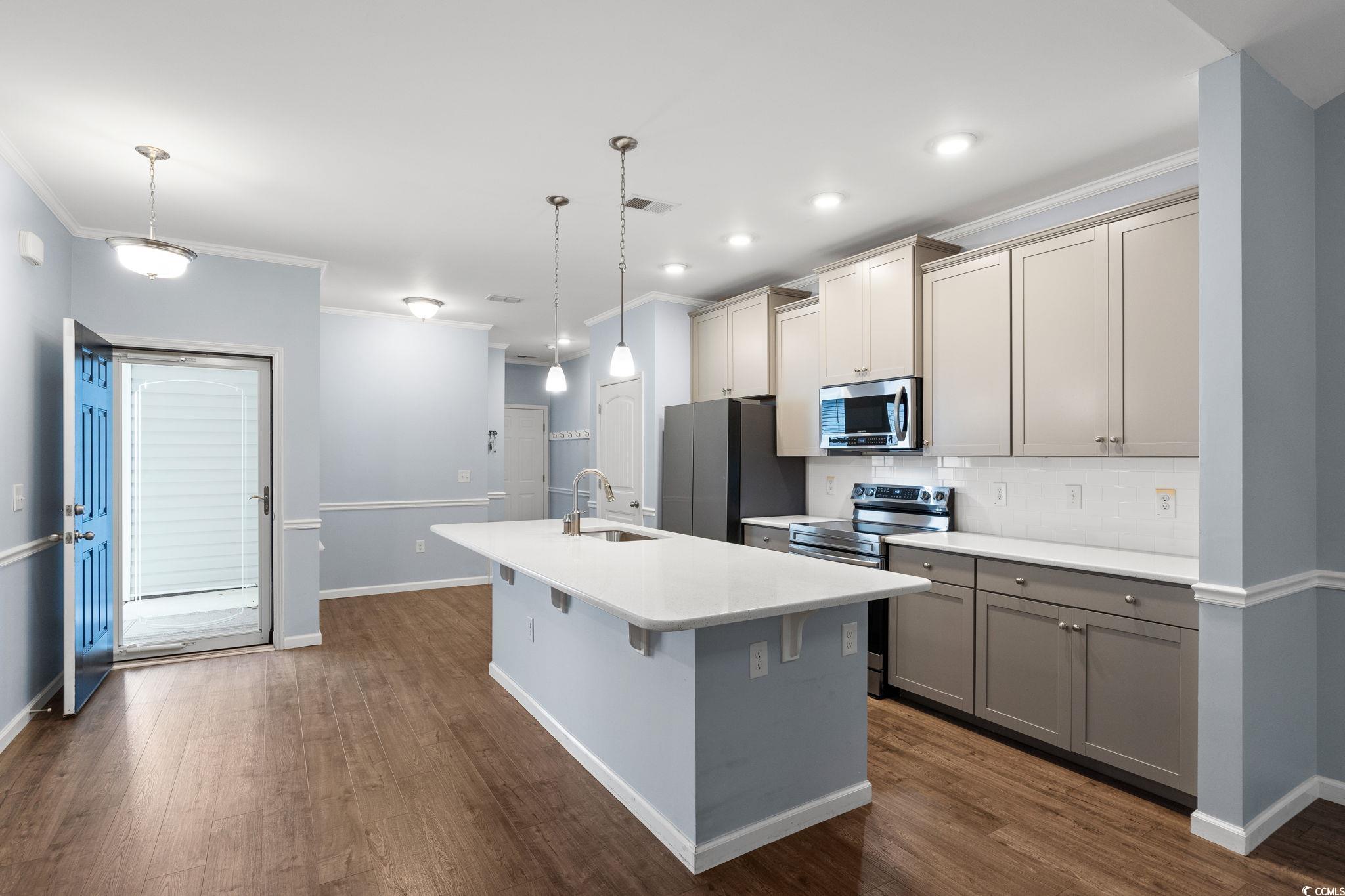 797 Salerno Circle, Unit C Myrtle Beach, SC 29579 - Photo 5 of 40 Kitchen with crown molding, stainless steel appliances, pendant lighting, gray cabinets, and a kitchen island with sink