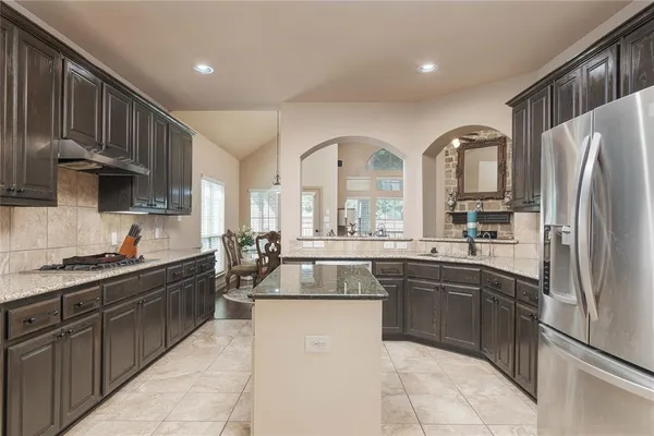 a kitchen with stainless steel appliances granite countertop a sink a stove and a refrigerator