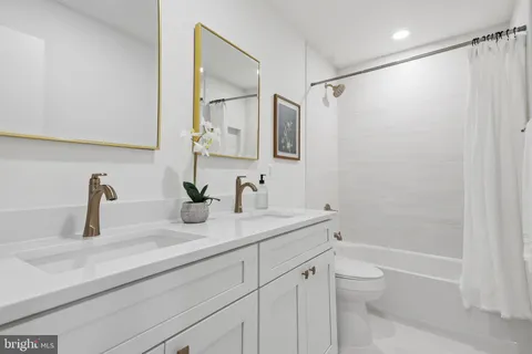 a bathroom with a granite countertop sink a toilet and a mirror