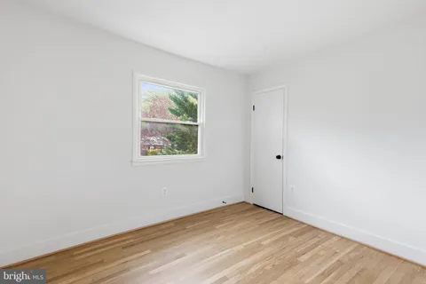 an empty room with wooden floor and window
