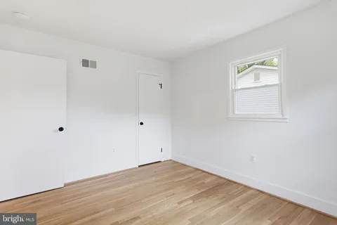 an empty room with wooden floor and window