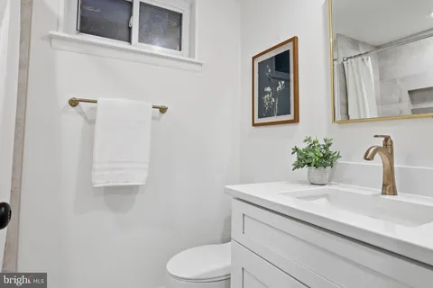 a bathroom with a granite countertop toilet sink and mirror
