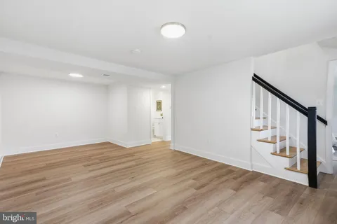 a view of an empty room with wooden floor and stairs