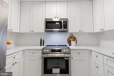 a kitchen with granite countertop white cabinets and stainless steel appliances