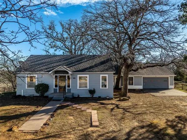 a front view of house with yard and trees in the background