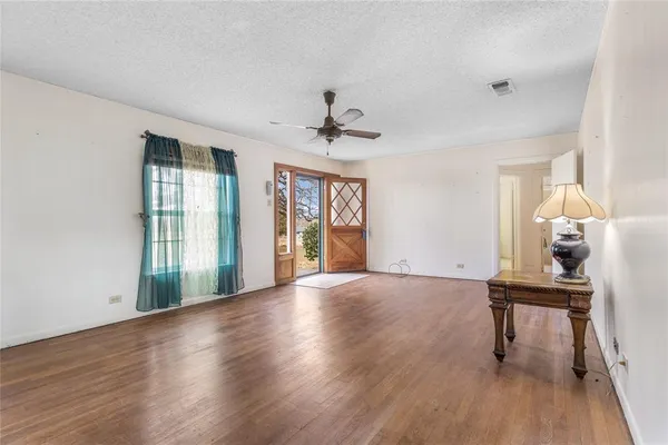 a view of an empty room with a window and wooden floor
