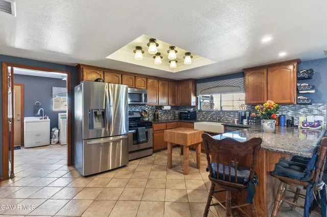 a kitchen with stainless steel appliances kitchen island granite countertop a refrigerator and microwave
