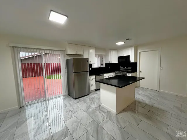 a kitchen with granite countertop a sink a refrigerator and a stove