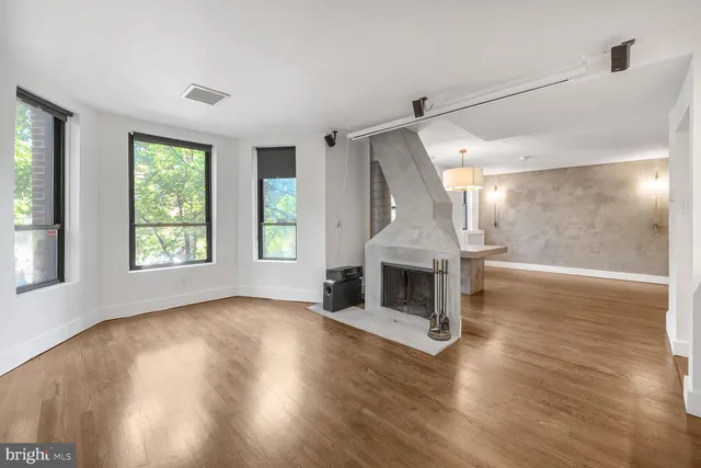 a view of a big room with wooden floor fireplace and windows