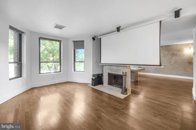 a view of a livingroom with wooden floor a fireplace and window