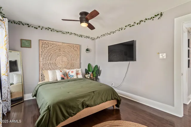 a bedroom with a bed a flat screen tv and a wall painting