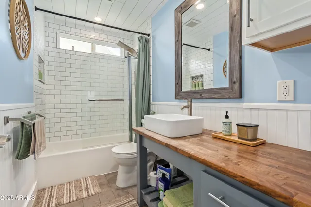 a bathroom with a granite countertop sink a toilet a mirror and shower